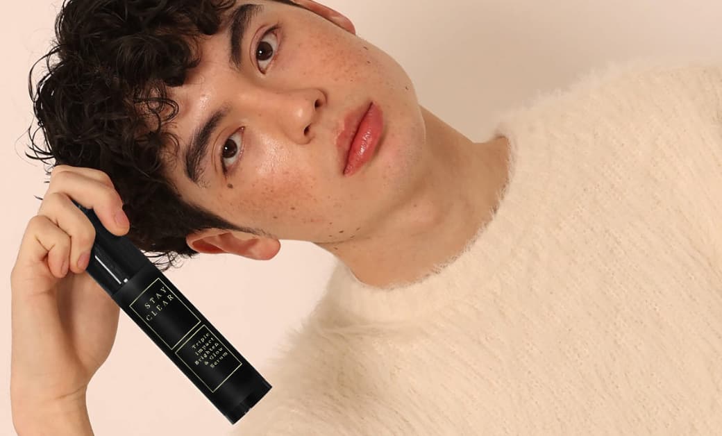 Man with clear, healthy skin holding Stay Clear Beauty Triple Impact Serum — clinical serum for sensitive and acne-prone skin."
