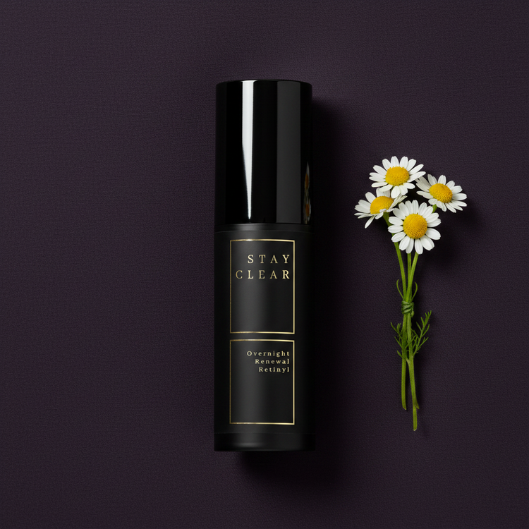 Stay Clear Beauty Overnight Renewal Retinyl bottle with chamomile flowers on a dark background — retinyl palmitate night treatment for clogged pores, cell turnover, and acne-prone skin.