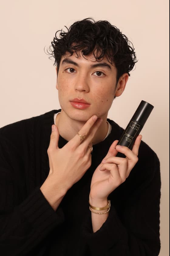 Man applying Stay Clear Beauty Overnight Renewal Retinyl Serum for Sensitive Skin to his face while holding the bottle — retinyl palmitate night serum for sensitive, acne-prone, and barrier-compromised skin.