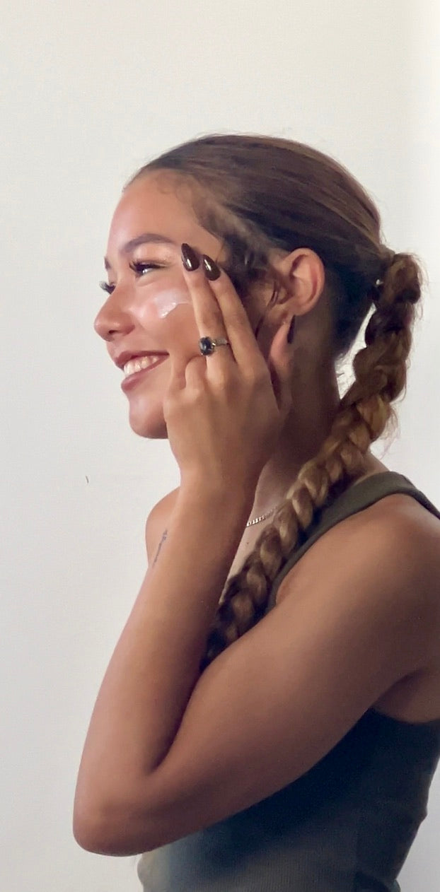 Smiling young woman with braids applying Stay Clear Beauty Peptide Power Play Lotion to cheek — copper peptide moisturizer for skin firmness, fine lines, collagen support, anti-aging, acne-prone skin