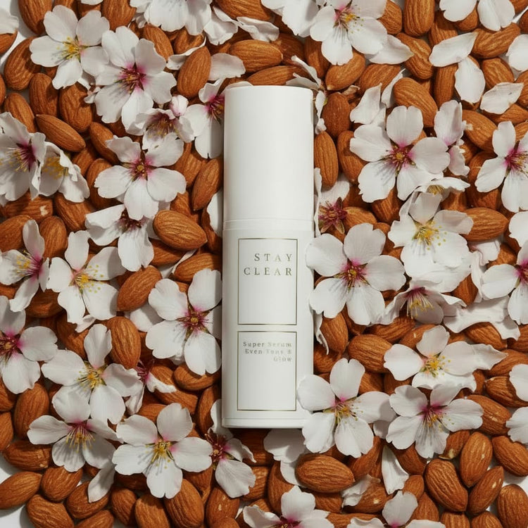 Stay Clear Beauty Super Serum Even Tone & Glow Sensitive surrounded by almond blossoms and botanicals on a flat lay — brightening serum for dark spots, post-acne marks, hyperpigmentation, and sensitive skin.
