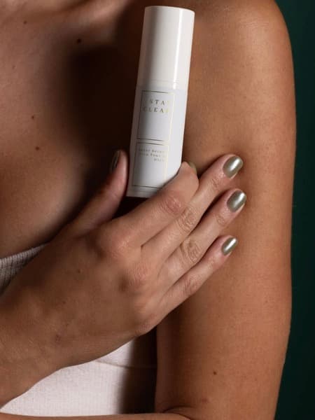 Woman holding Stay Clear Beauty Super Serum Even Tone &amp; Glow against her shoulder — mandelic acid brightening serum for dark spots, post-acne marks, uneven skin tone, and sensitive acne-prone skin.

