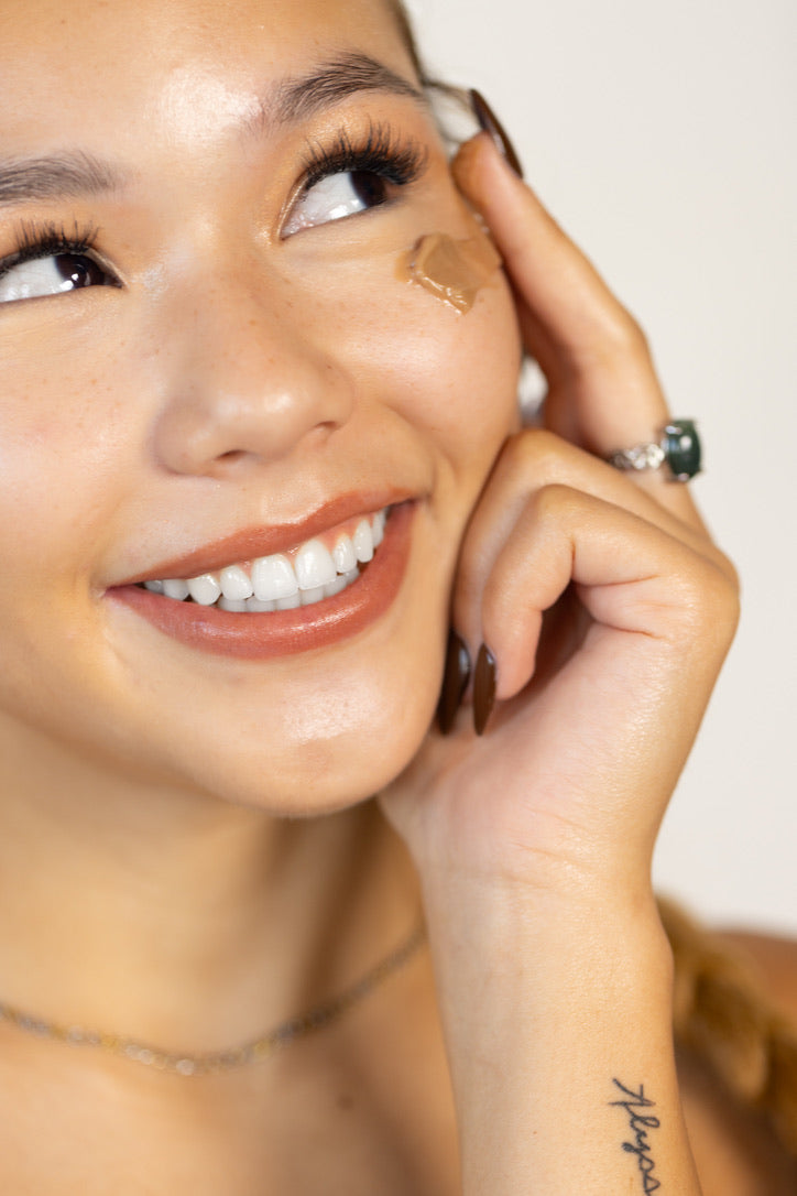 A woman gently applying Stay Clear lotion to her face, highlighting its hydrating and soothing properties for a radiant complexion.