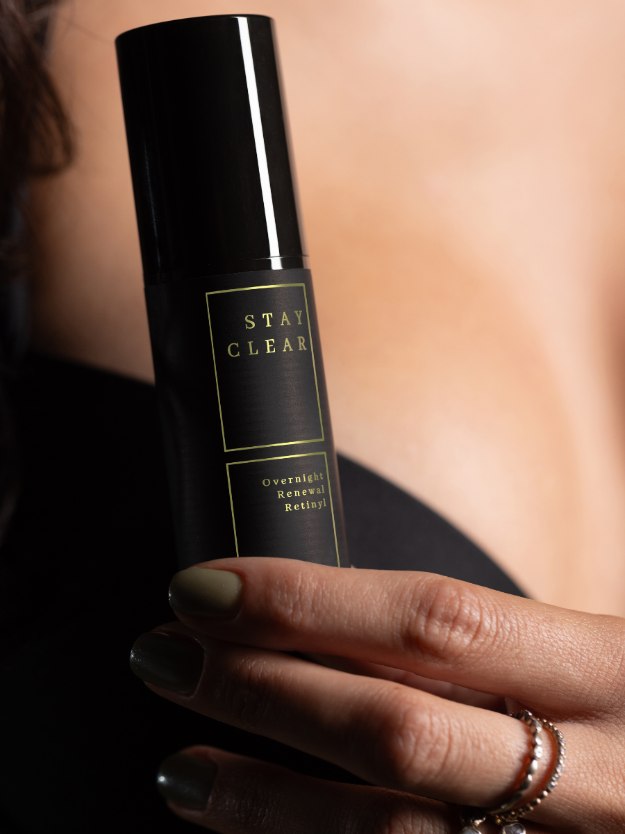 Woman’s hand holding Stay Clear Overnight Renewal Retinyl serum in soft natural light