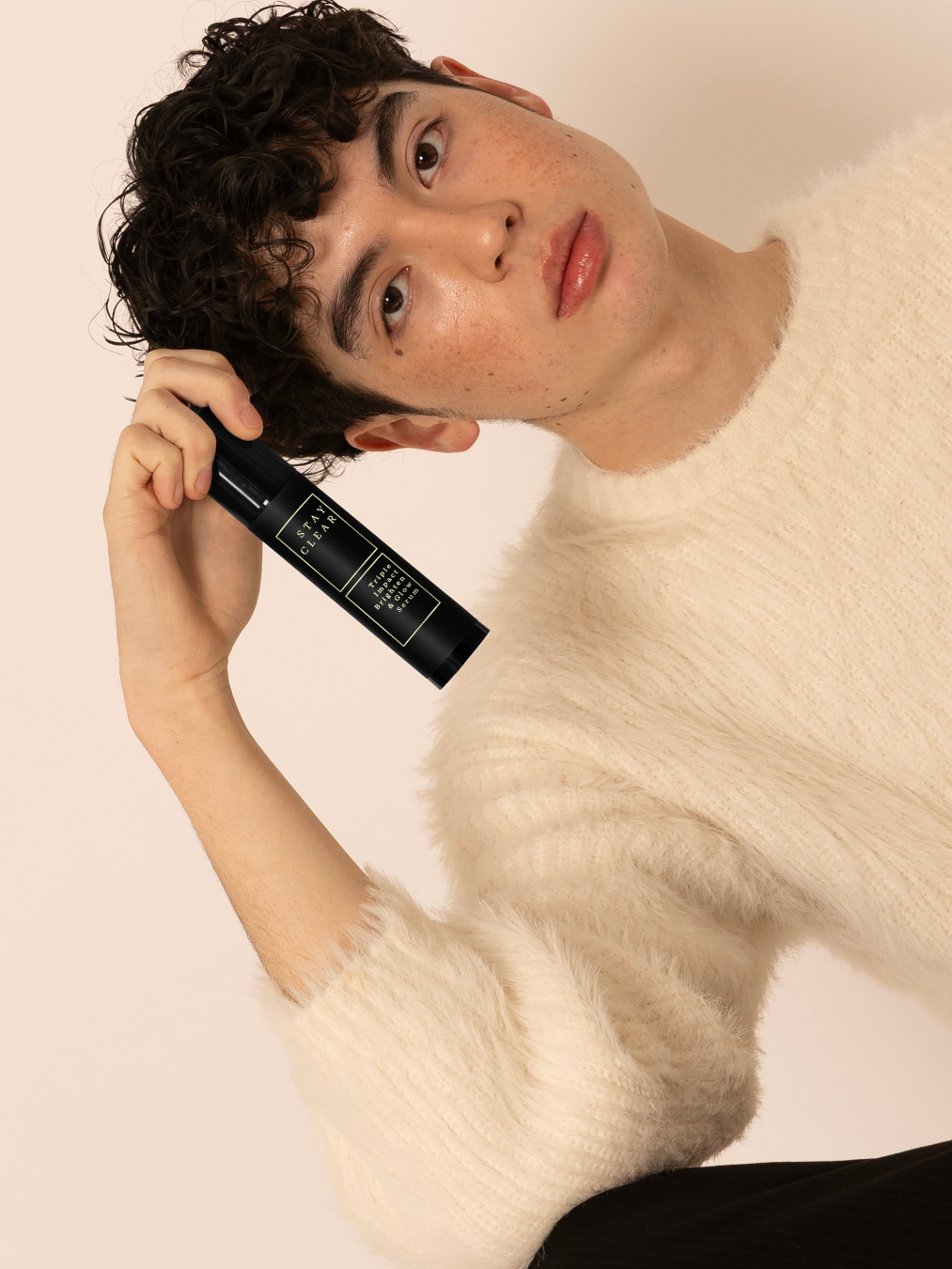 Young man with clear skin holding Stay Clear Beauty Triple Impact Brighten & Glow Serum — brightening serum for dark spots, post-acne marks, and uneven skin tone.