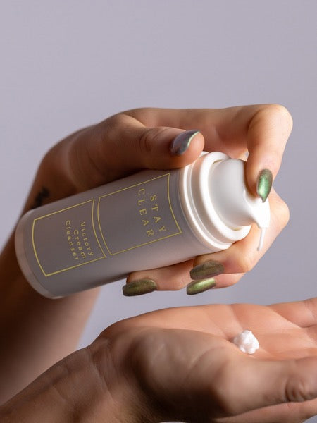 A woman’s hands holding Stay Clear cream cleanser, highlighting its rich, hydrating formula designed to gently cleanse and protect dry, sensitive skin in extreme climates.